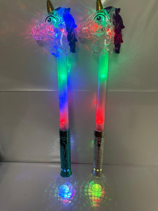 Two toy wands with unicorn designs, one with a blue head and the other with a purple head, both with multicolored bodies and standing upright.